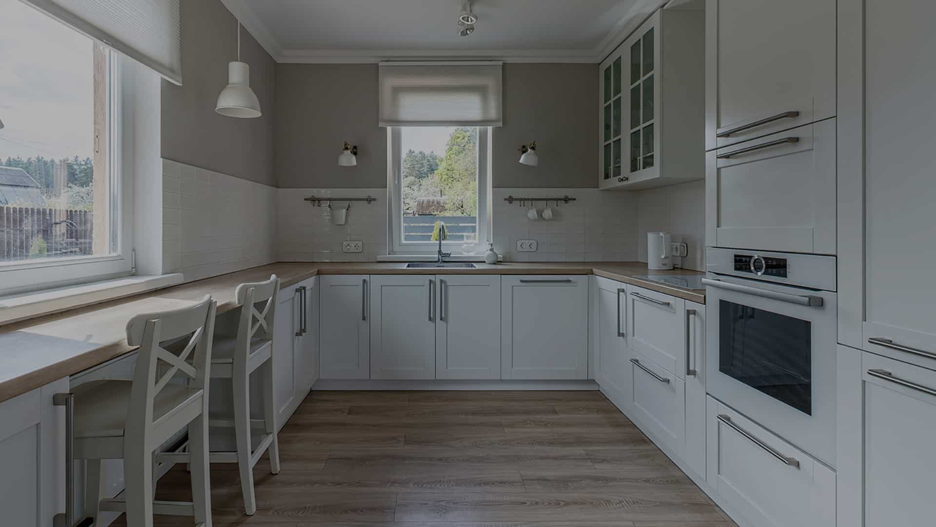 Bright white kitchen with a window and dining chairs